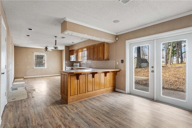 kitchen with electric range, sink, light hardwood / wood-style flooring, kitchen peninsula, and a textured ceiling