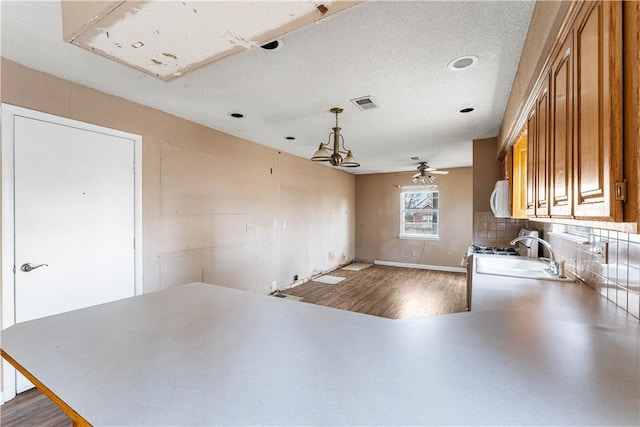 kitchen featuring ceiling fan, sink, kitchen peninsula, pendant lighting, and a textured ceiling