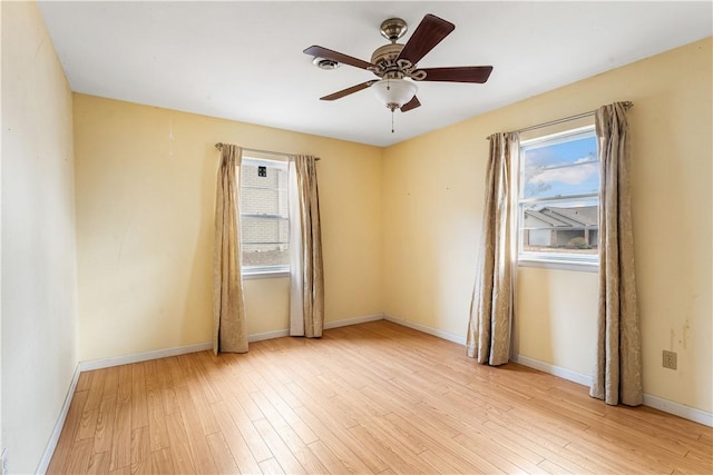 spare room featuring plenty of natural light, ceiling fan, and light wood-type flooring