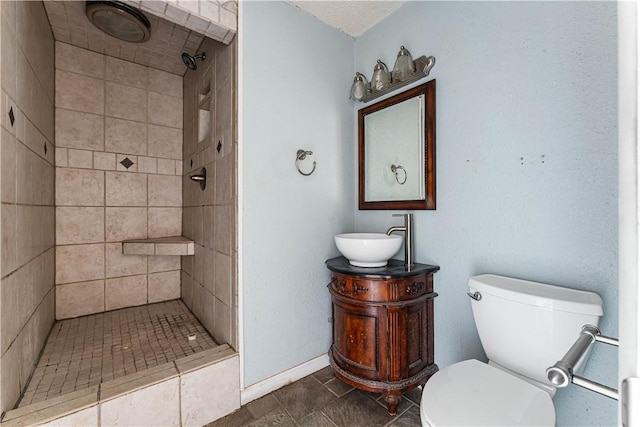 bathroom with a tile shower, vanity, and toilet