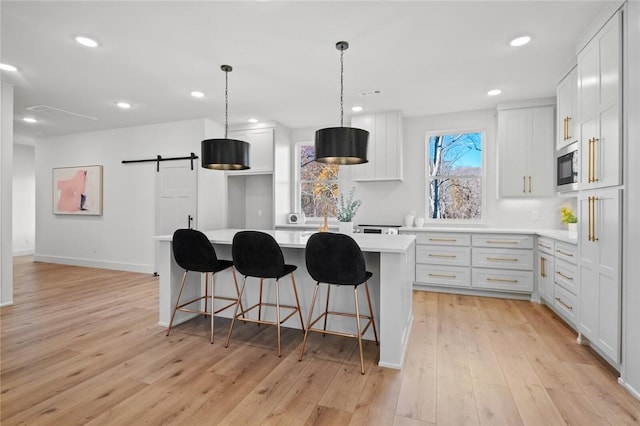 8893 Williams Rd, Rogers, AR 72756 - kitchen with light countertops, light wood-type flooring, a center island, built in microwave, and a breakfast bar