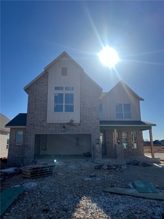 view of front of house featuring an attached garage, board and batten siding, and brick siding