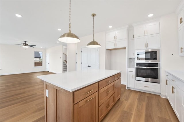 445 Fox Trl, Elm Springs, AR 72762 - kitchen with light countertops, oven, black microwave, and light wood-style flooring