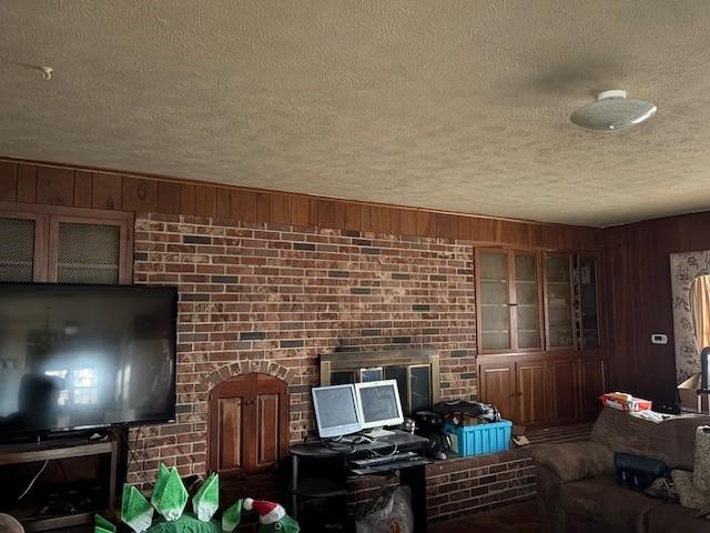 living room with brick wall, a textured ceiling, and wood walls