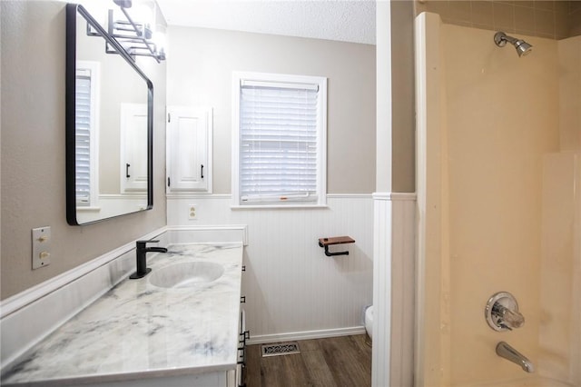 full bathroom with shower / bathing tub combination, vanity, wood-type flooring, a textured ceiling, and toilet