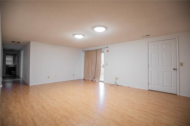 spare room with a textured ceiling and light hardwood / wood-style flooring