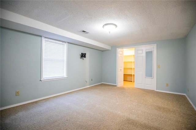 carpeted empty room featuring a textured ceiling