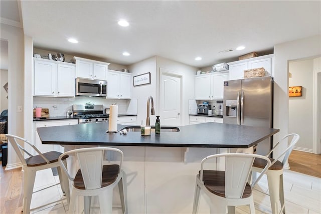 kitchen with white cabinets, an island with sink, and stainless steel appliances