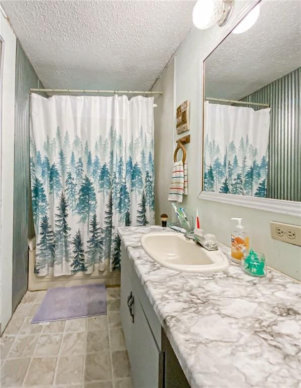 bathroom featuring shower / bathtub combination with curtain, vanity, and a textured ceiling