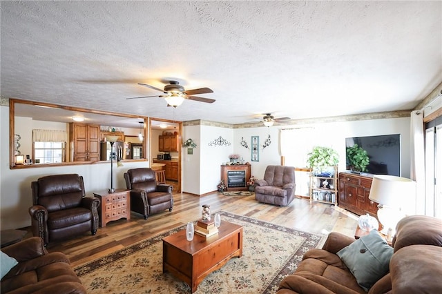 living room featuring ceiling fan, hardwood / wood-style floors, and a textured ceiling