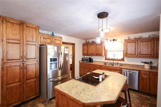 kitchen with pendant lighting, sink, stainless steel appliances, a center island, and a textured ceiling