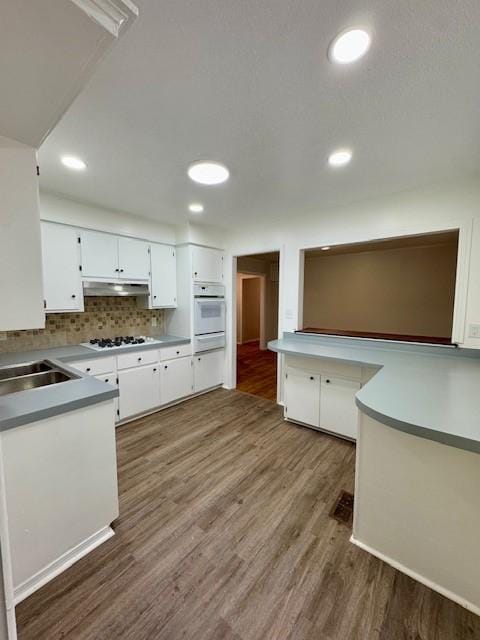 kitchen featuring white cabinets, dark hardwood / wood-style floors, tasteful backsplash, and white gas cooktop