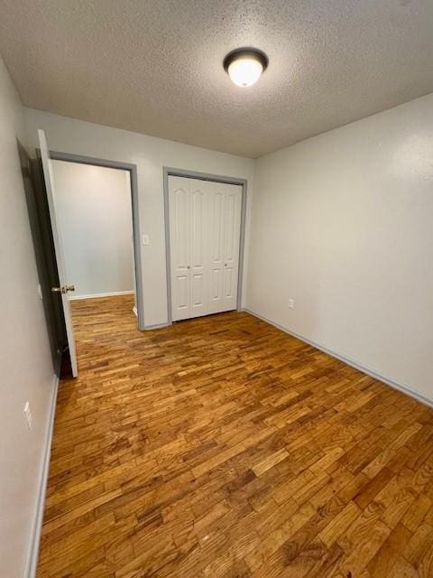 unfurnished bedroom with a closet, light hardwood / wood-style flooring, and a textured ceiling