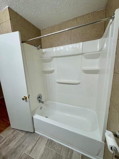 bathroom with shower / bathing tub combination and a textured ceiling