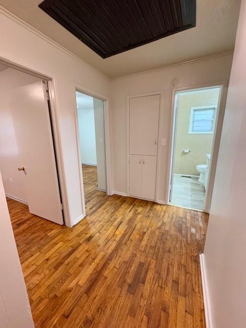 hall with light hardwood / wood-style floors and ornamental molding