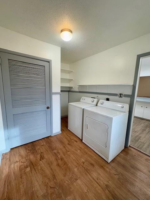 laundry room featuring washing machine and dryer, wood-type flooring, and a textured ceiling