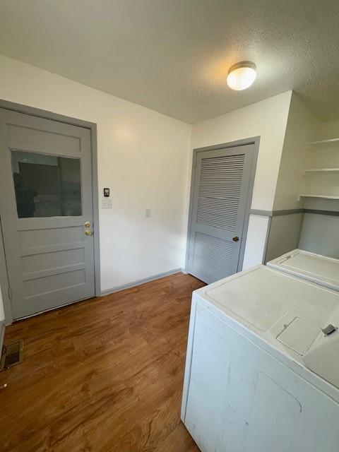 laundry area featuring dark hardwood / wood-style flooring, separate washer and dryer, and a textured ceiling