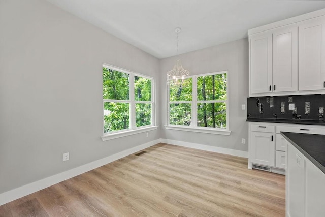 kitchen with tasteful backsplash, light hardwood / wood-style flooring, white cabinets, and pendant lighting