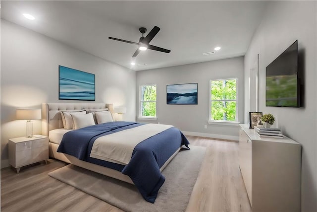 bedroom with ceiling fan, light hardwood / wood-style flooring, and multiple windows