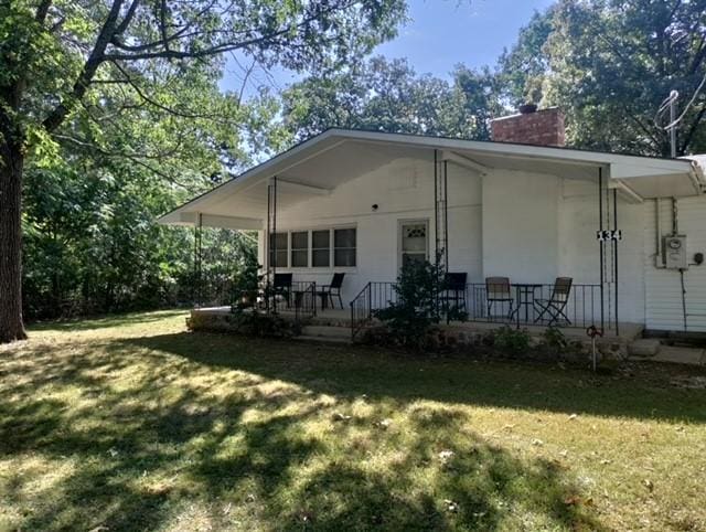 rear view of property featuring a yard and covered porch