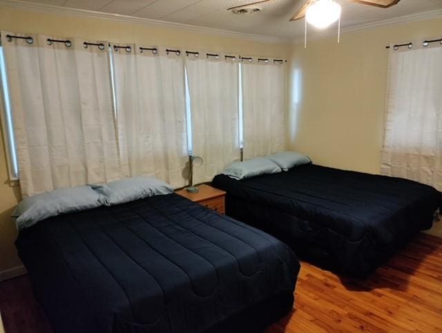 bedroom featuring ceiling fan, hardwood / wood-style floors, and crown molding