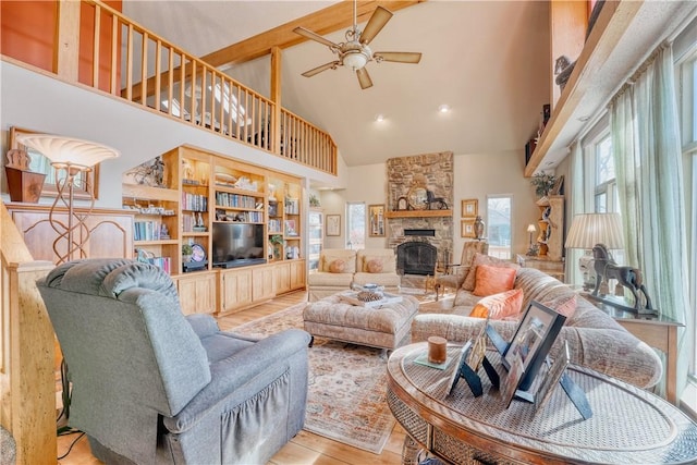 living room with ceiling fan, a fireplace, high vaulted ceiling, and light hardwood / wood-style floors