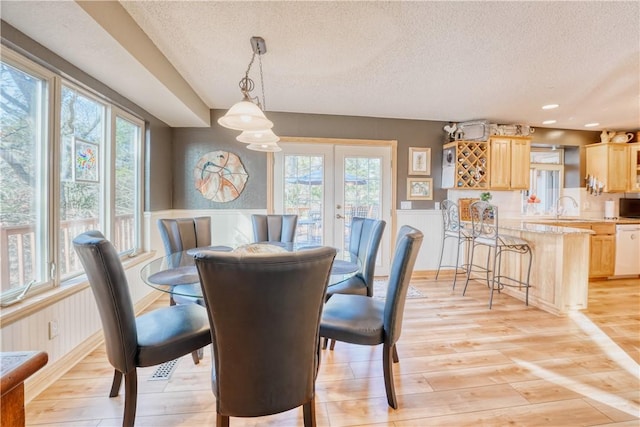 dining space with a textured ceiling, light hardwood / wood-style flooring, and sink