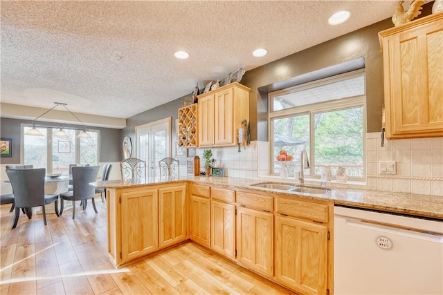 kitchen with dishwasher, kitchen peninsula, a wealth of natural light, and sink