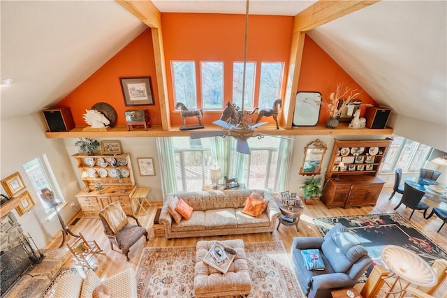 living room featuring hardwood / wood-style floors, ceiling fan, lofted ceiling with beams, and a stone fireplace