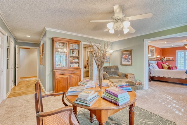 sitting room featuring a textured ceiling, ceiling fan, crown molding, and light carpet