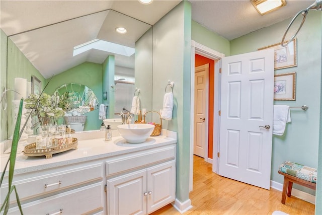 bathroom featuring vanity, hardwood / wood-style flooring, and lofted ceiling