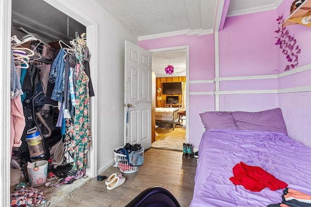 bedroom with a textured ceiling, a closet, wood finished floors, and crown molding