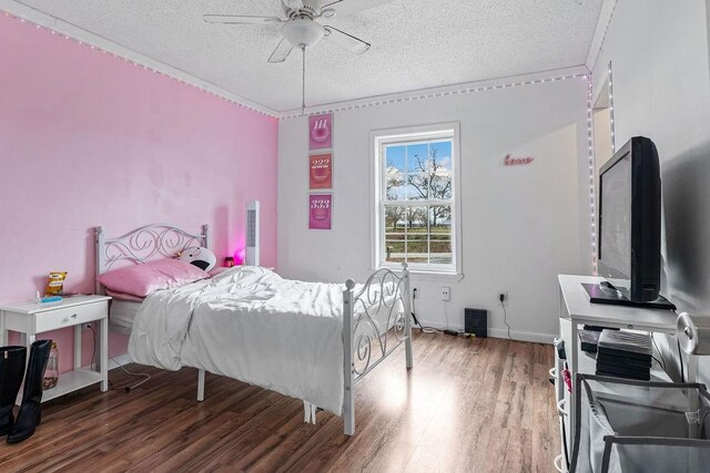 bedroom with hardwood / wood-style flooring, ceiling fan, and a textured ceiling