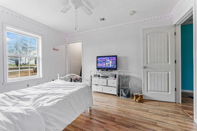 bedroom with a textured ceiling, light hardwood / wood-style flooring, and ceiling fan