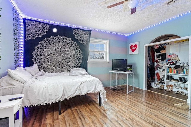 bedroom featuring ceiling fan, hardwood / wood-style floors, and a textured ceiling