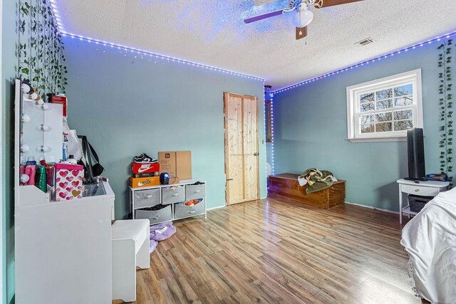 bedroom with ceiling fan, light hardwood / wood-style flooring, and a textured ceiling