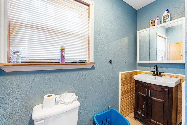 bathroom featuring a textured wall, vanity, and toilet