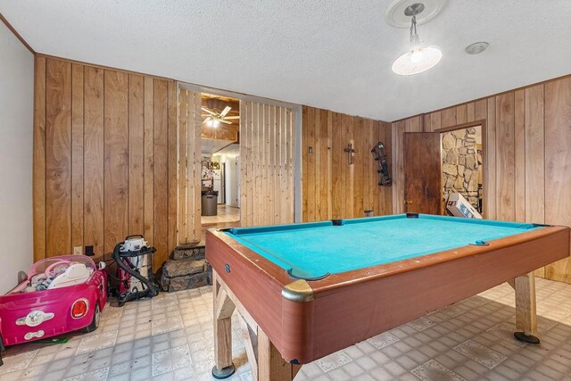 game room featuring wooden walls, a textured ceiling, and pool table