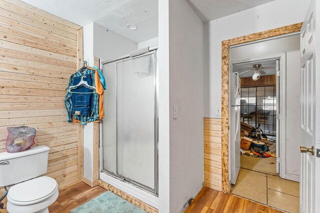 bathroom with wood walls, a shower with door, and hardwood / wood-style flooring