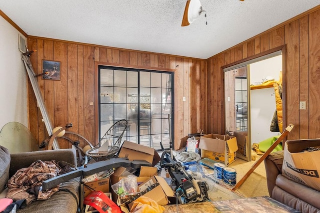 misc room featuring carpet, wooden walls, ceiling fan, and a textured ceiling