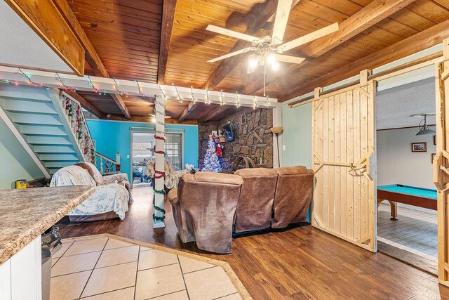 living room with beamed ceiling, a barn door, wood-type flooring, and wood ceiling