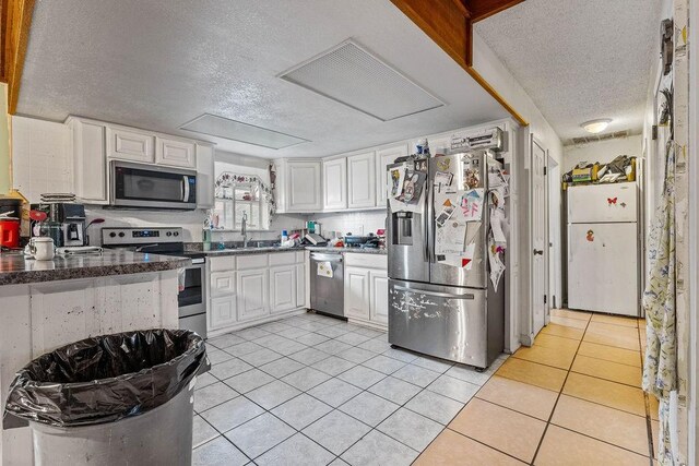 kitchen featuring white cabinets, sink, a textured ceiling, appliances with stainless steel finishes, and light tile patterned flooring