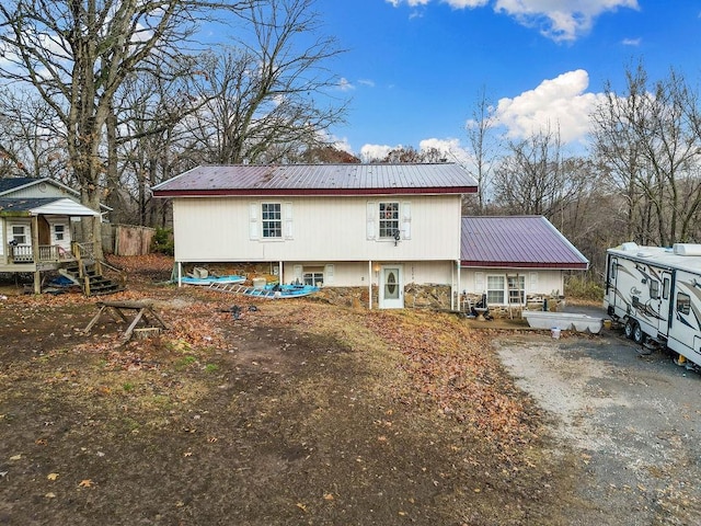 rear view of property with driveway and metal roof