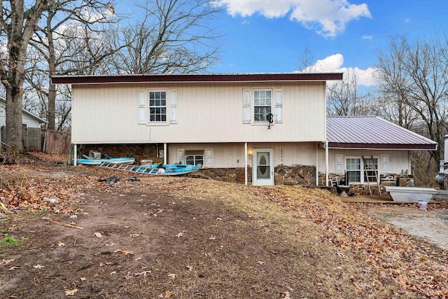 rear view of house with metal roof and stone siding