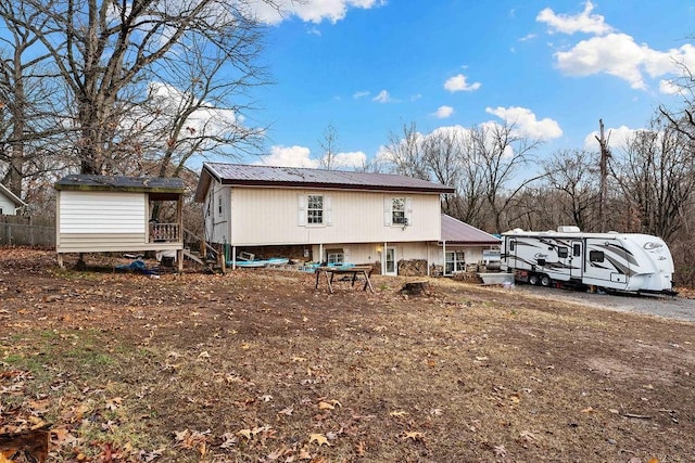 back of house featuring metal roof and an outdoor structure