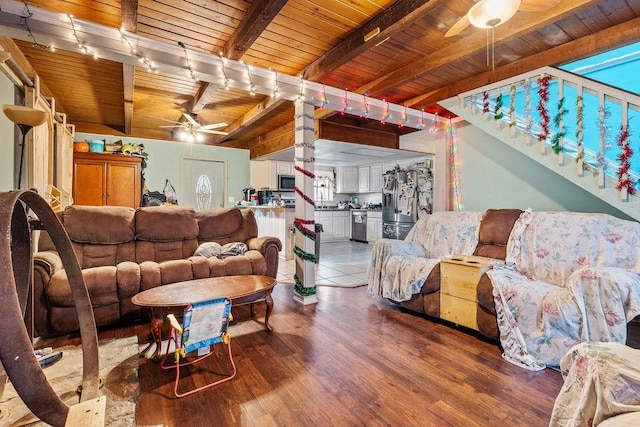 living area featuring ceiling fan, light wood finished floors, wooden ceiling, and beam ceiling