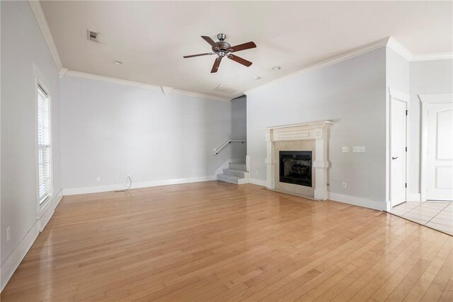 3706 Cherokee Rd, Rogers, AR 72758 - unfurnished living room with visible vents, a tiled fireplace, light wood-style floors, ornamental molding, and stairs