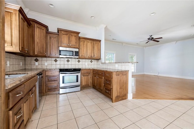 3706 Cherokee Rd, Rogers, AR 72758 - kitchen featuring a peninsula, appliances with stainless steel finishes, brown cabinetry, and backsplash