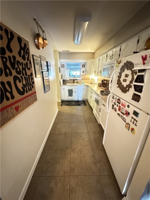 kitchen featuring white cabinetry, white appliances, sink, and dark tile patterned floors