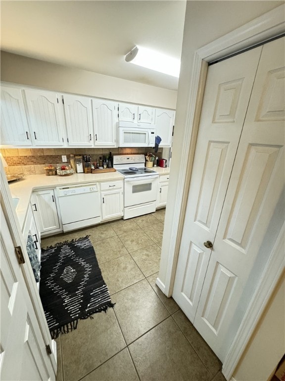 kitchen featuring backsplash, light tile patterned floors, white cabinets, and white appliances